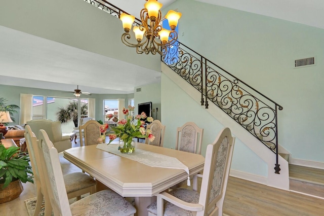 dining space with hardwood / wood-style flooring and ceiling fan with notable chandelier