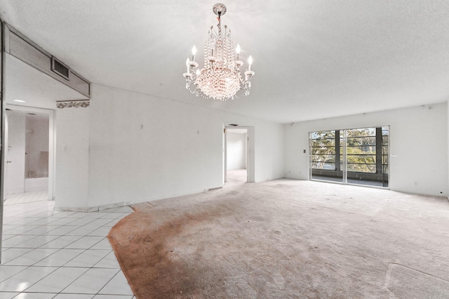 tiled spare room with an inviting chandelier and a textured ceiling