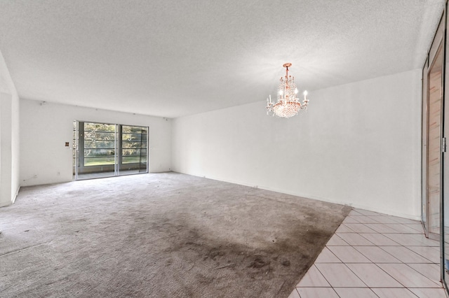 carpeted spare room with a notable chandelier and a textured ceiling