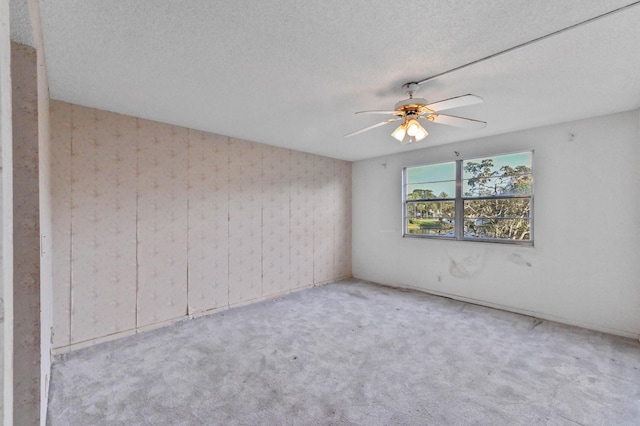 carpeted spare room featuring ceiling fan and a textured ceiling