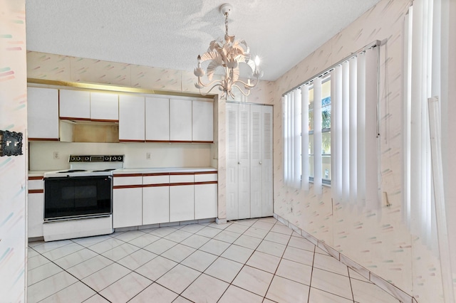 kitchen with white cabinetry, decorative light fixtures, a textured ceiling, a notable chandelier, and white range with electric stovetop