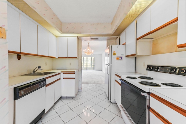 kitchen with pendant lighting, sink, white appliances, white cabinetry, and light carpet