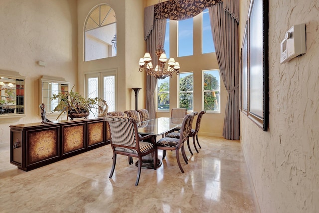 dining area featuring plenty of natural light, a towering ceiling, an inviting chandelier, and french doors