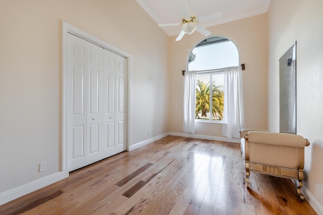 bedroom with light hardwood / wood-style flooring, a high ceiling, ceiling fan, crown molding, and a closet