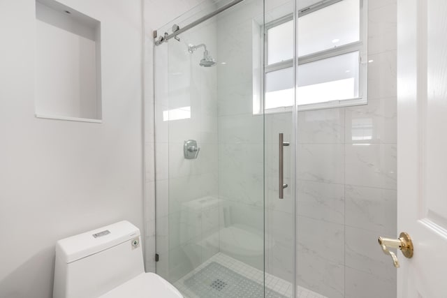 bathroom featuring a shower with shower door and toilet