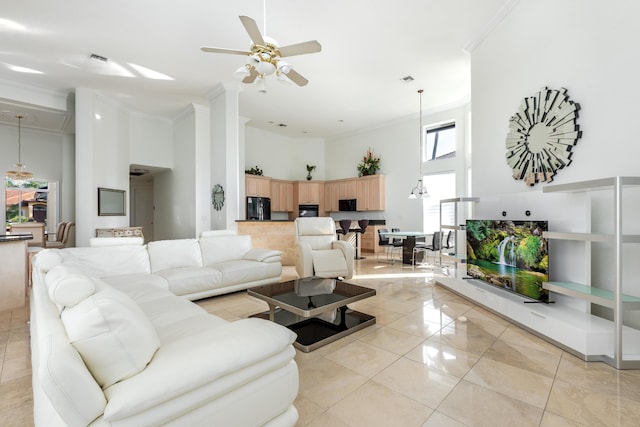 living room featuring light tile patterned floors, a towering ceiling, ornamental molding, and ceiling fan