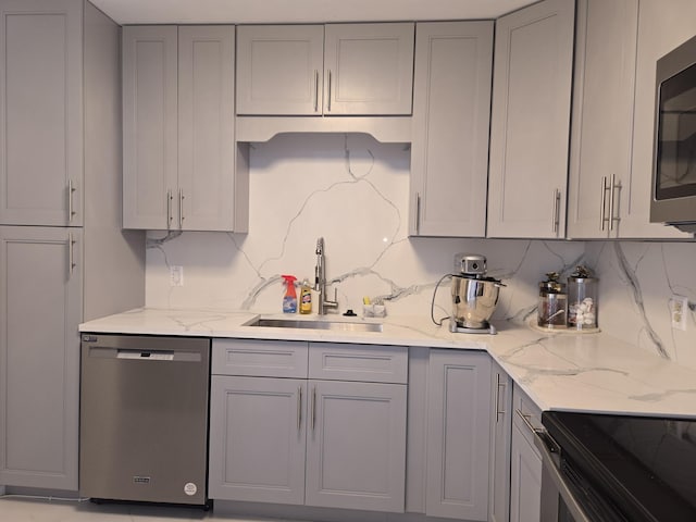 kitchen featuring gray cabinetry, sink, light stone countertops, and appliances with stainless steel finishes