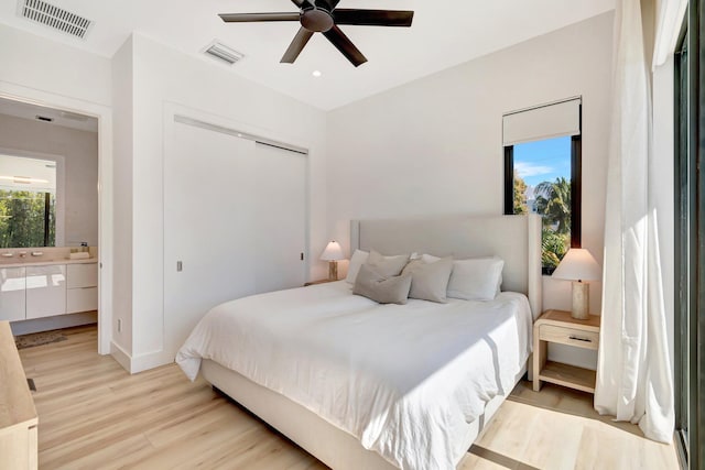 bedroom with ensuite bath, light hardwood / wood-style flooring, a closet, and ceiling fan