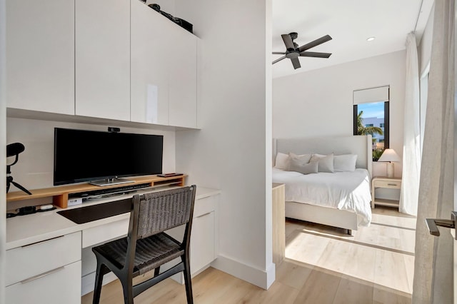 home office with ceiling fan, built in desk, and light hardwood / wood-style floors