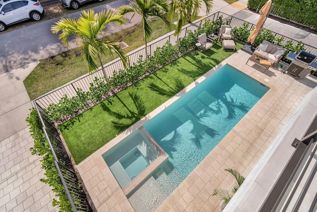 view of swimming pool with a patio, a yard, and an in ground hot tub