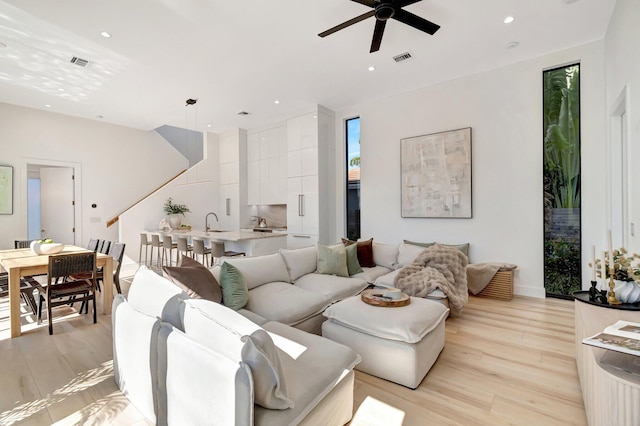 living room with sink, ceiling fan, and light hardwood / wood-style flooring