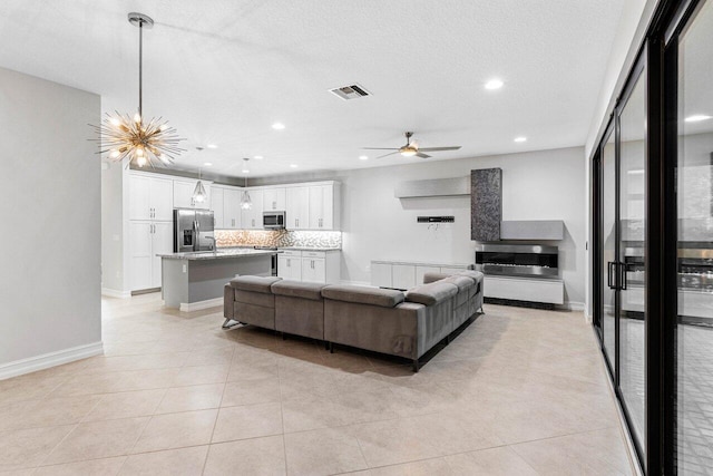 living room with ceiling fan with notable chandelier, a textured ceiling, and light tile patterned floors