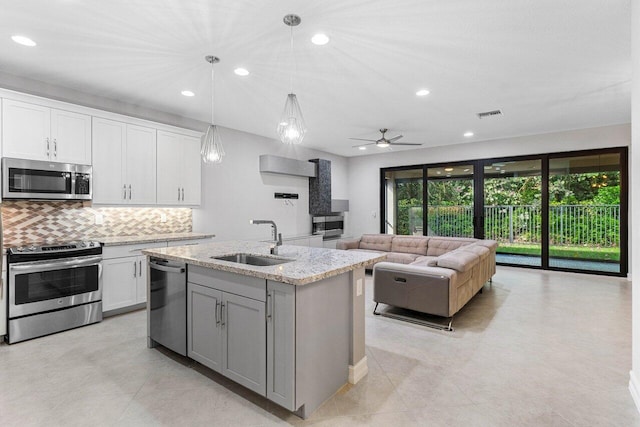 kitchen featuring sink, white cabinetry, a kitchen island with sink, stainless steel appliances, and decorative light fixtures