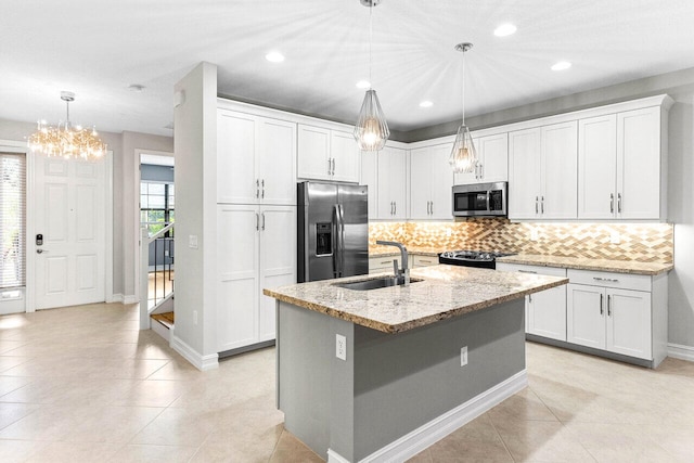 kitchen featuring an island with sink, sink, white cabinets, hanging light fixtures, and stainless steel appliances