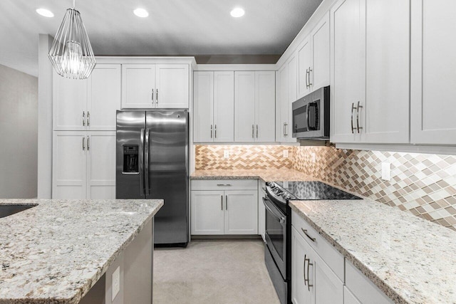 kitchen with white cabinetry, light stone counters, decorative light fixtures, appliances with stainless steel finishes, and backsplash