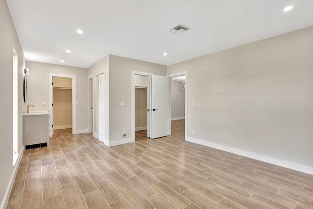 unfurnished bedroom with sink, a spacious closet, and light hardwood / wood-style flooring