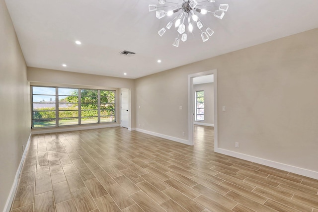 spare room featuring a notable chandelier and light wood-type flooring