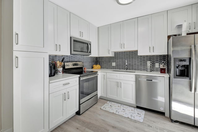 kitchen with sink, backsplash, white cabinets, and appliances with stainless steel finishes