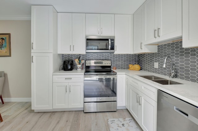 kitchen featuring sink, white cabinetry, tasteful backsplash, light hardwood / wood-style flooring, and appliances with stainless steel finishes