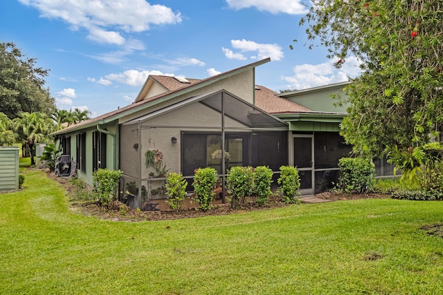 rear view of property featuring a yard and a sunroom