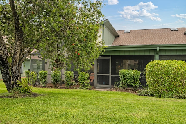 rear view of house with a yard and a sunroom