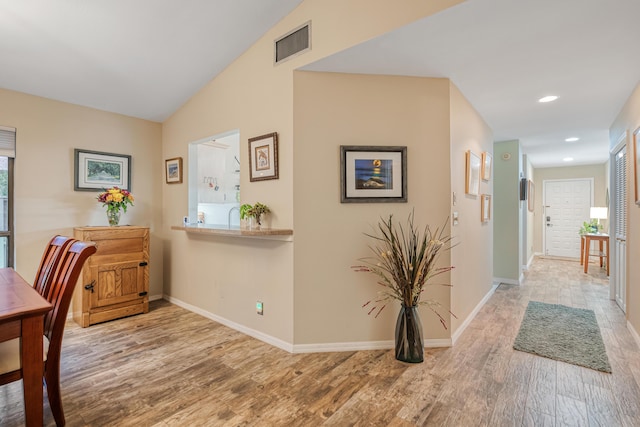 hall with lofted ceiling and hardwood / wood-style floors