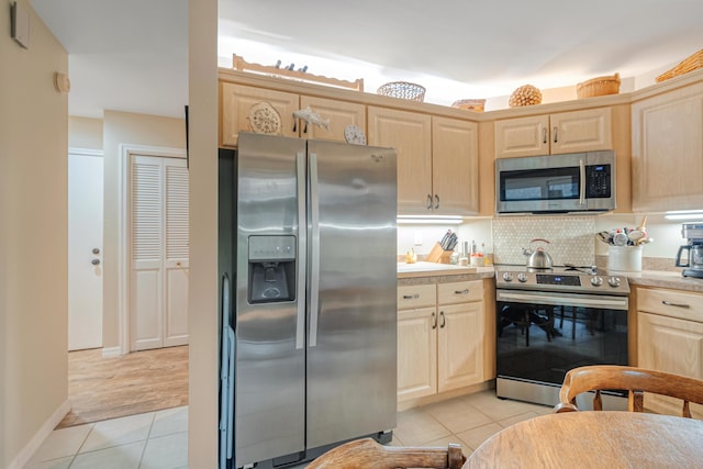 kitchen featuring tasteful backsplash, light tile patterned floors, light brown cabinets, and appliances with stainless steel finishes