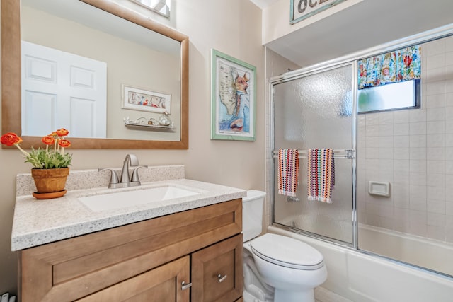 full bathroom with enclosed tub / shower combo, vanity, and toilet