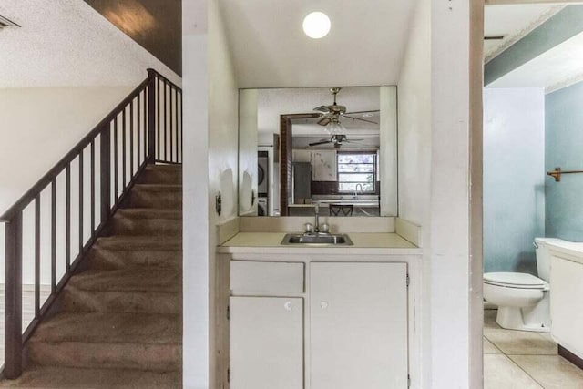 interior space featuring ceiling fan, stacked washer / dryer, vanity, tile patterned floors, and toilet