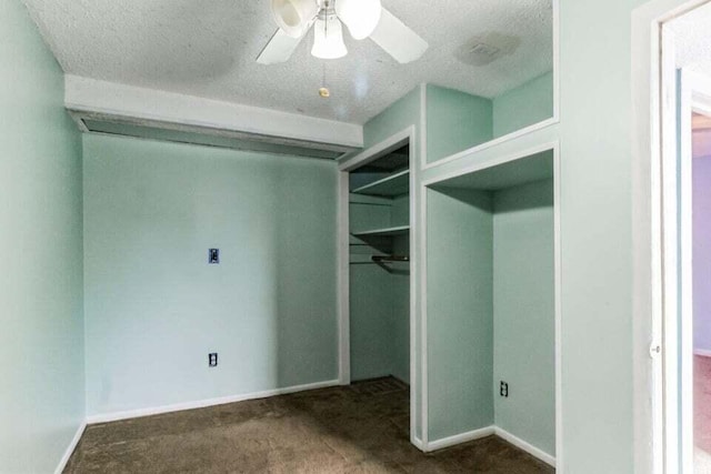 spacious closet featuring ceiling fan and dark carpet