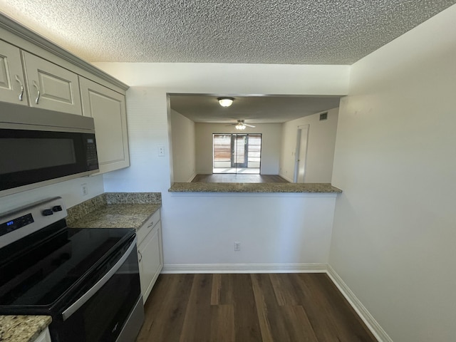 kitchen with dark wood-type flooring, ceiling fan, stainless steel appliances, a textured ceiling, and kitchen peninsula