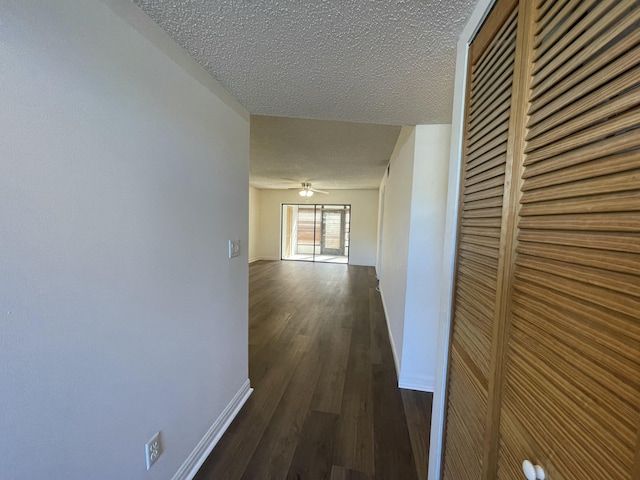 hallway with dark wood-type flooring and a textured ceiling