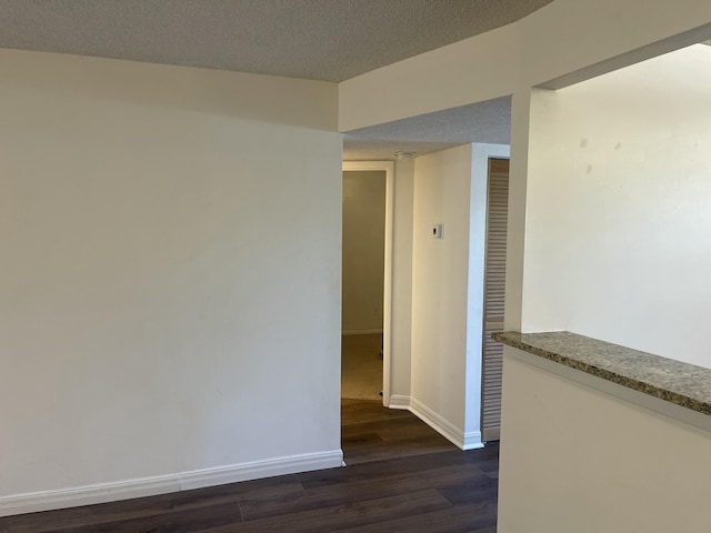 spare room featuring dark hardwood / wood-style floors and a textured ceiling