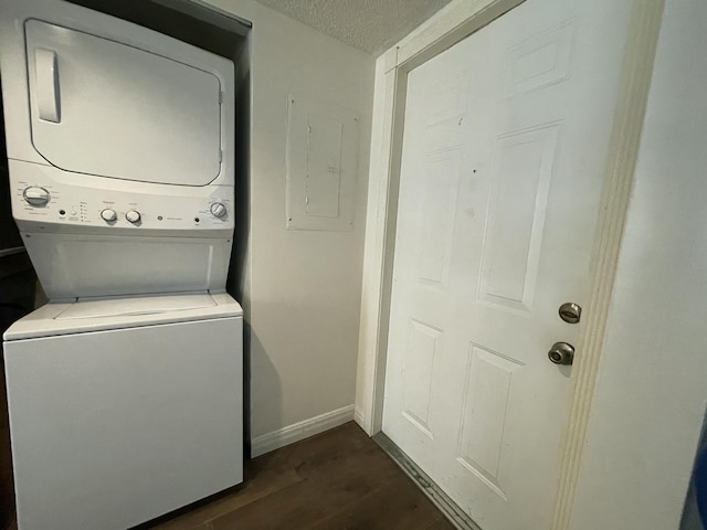 washroom featuring stacked washer and dryer, dark hardwood / wood-style floors, electric panel, and a textured ceiling