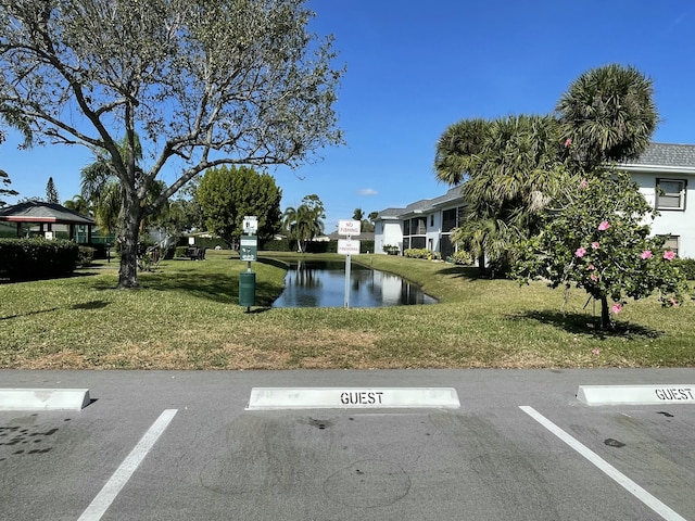 view of parking featuring a water view and a lawn