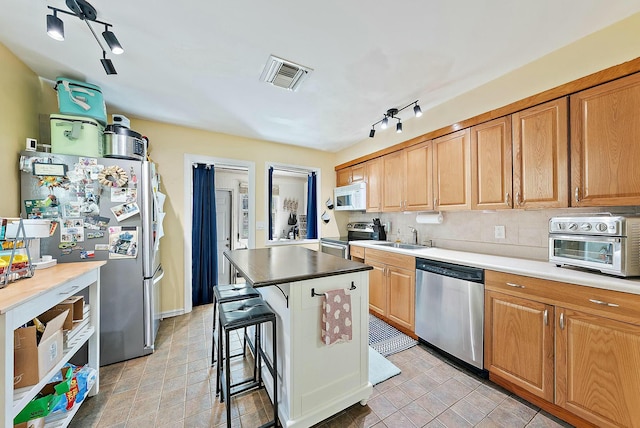 kitchen with sink, a breakfast bar area, a center island, appliances with stainless steel finishes, and decorative backsplash