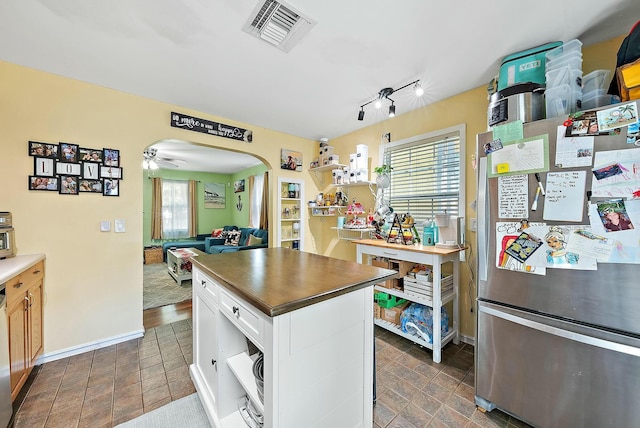 kitchen with white cabinets, dishwasher, a kitchen island, and stainless steel fridge