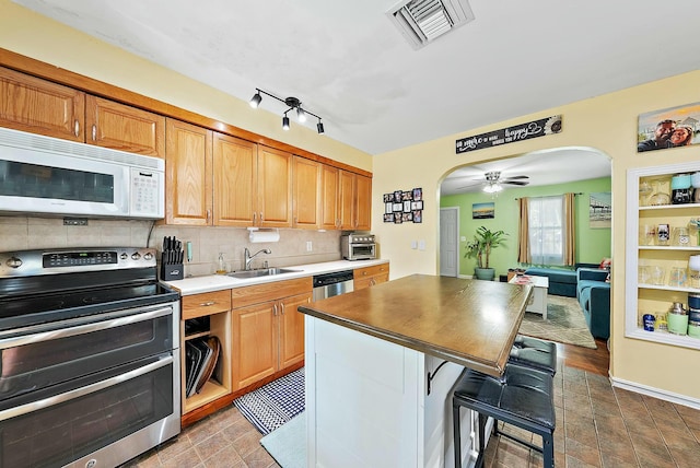 kitchen featuring sink, stainless steel appliances, a kitchen breakfast bar, tasteful backsplash, and a kitchen island