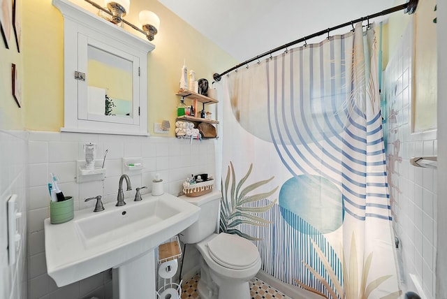 bathroom featuring toilet, curtained shower, sink, and tile walls