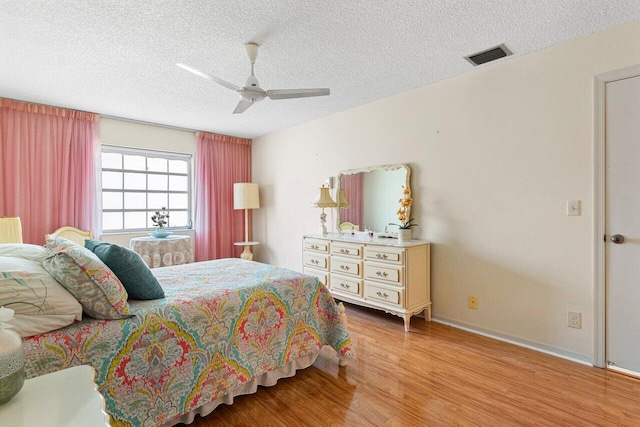 bedroom with ceiling fan, a textured ceiling, and light wood-type flooring