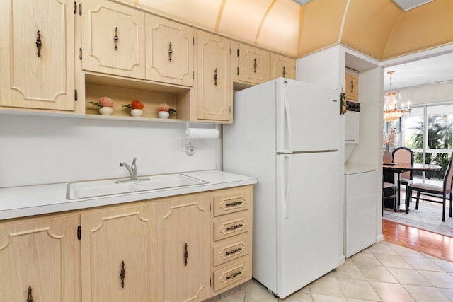 kitchen featuring white fridge, sink, light tile patterned floors, and a notable chandelier