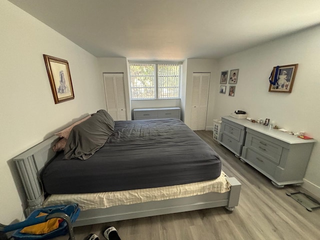 bedroom with multiple closets and light wood-type flooring