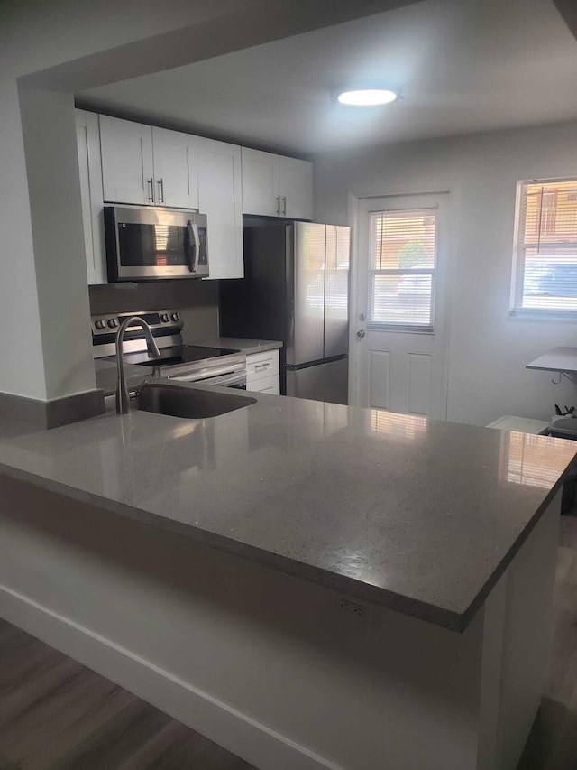 kitchen featuring white cabinetry, stone countertops, kitchen peninsula, and appliances with stainless steel finishes