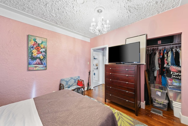 bedroom with hardwood / wood-style flooring, a textured ceiling, a chandelier, and a closet