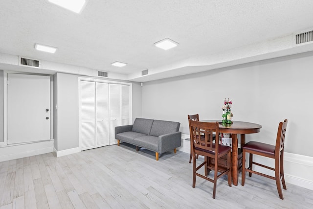 dining area with a textured ceiling and light wood-type flooring