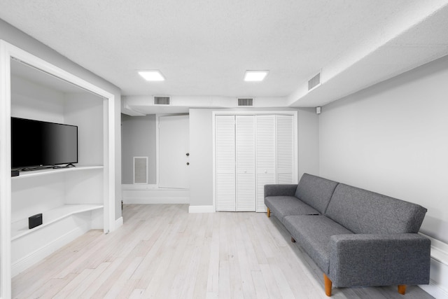 living room featuring a textured ceiling and light hardwood / wood-style flooring