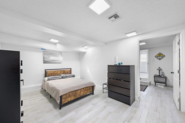 bedroom featuring light hardwood / wood-style flooring and a textured ceiling