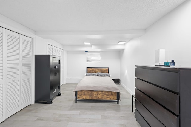 bedroom with light hardwood / wood-style floors, a closet, and a textured ceiling