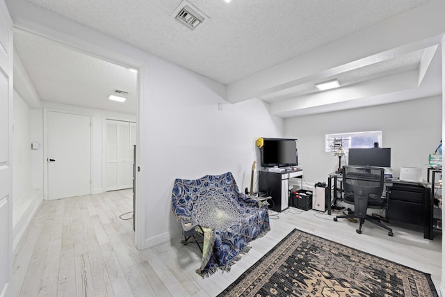 office area with a textured ceiling and light wood-type flooring