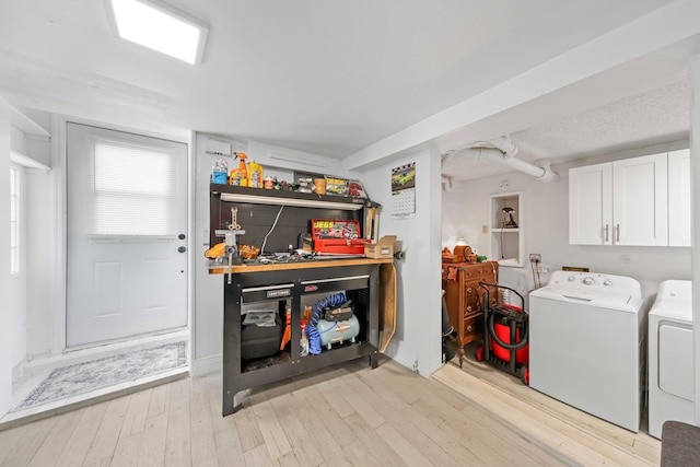 laundry room featuring cabinets, light wood-type flooring, and washing machine and clothes dryer